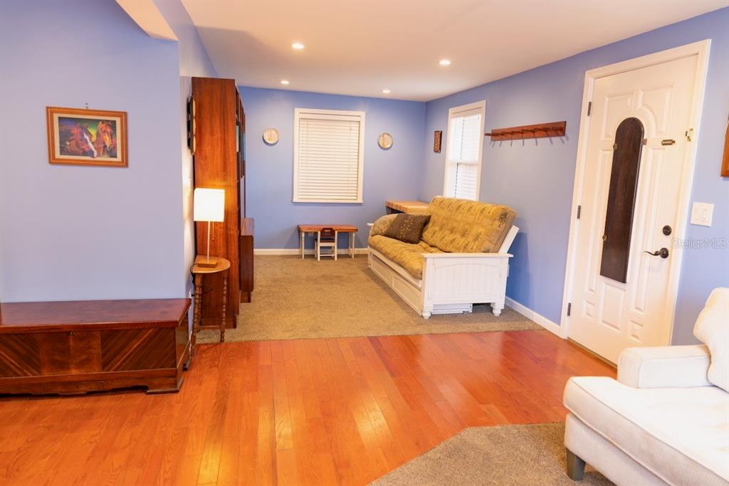 A living room features blue walls, hardwood and carpeted flooring, a white sofa, and a door — 544 FARNUM DRIVE, TARPON SPRINGS, FL