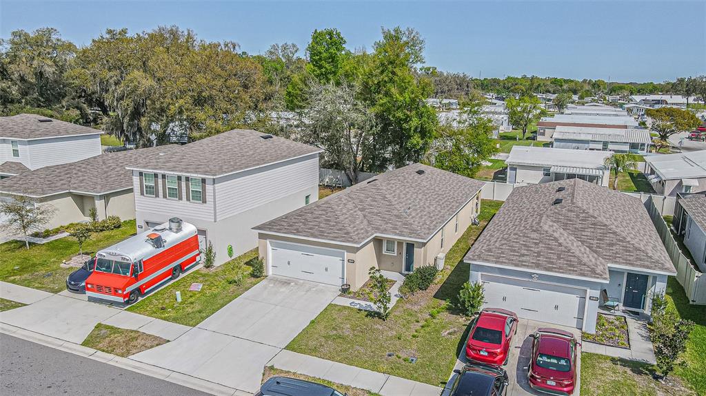 An aerial view shows three suburban houses with driveways and parked vehicles on a sunny day — 35045 JOMAR AVENUE, ZEPHYRHILLS, FL