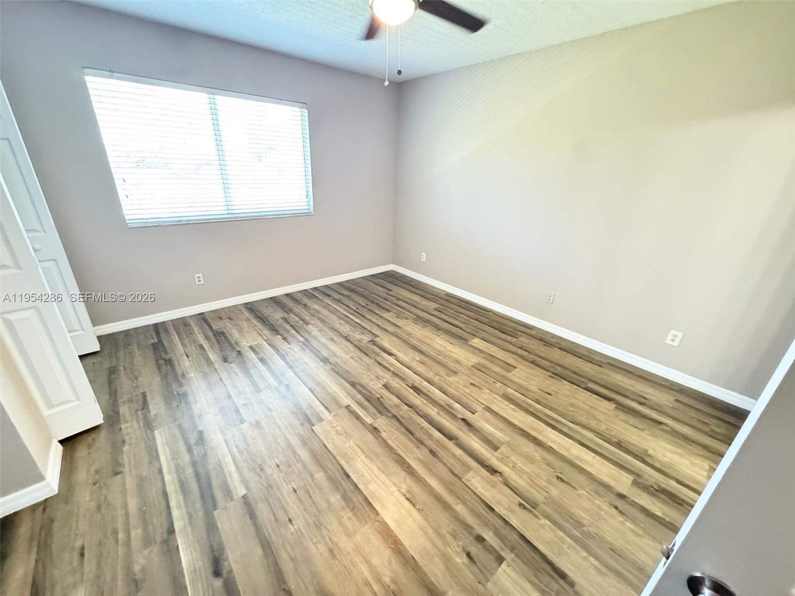 An empty bedroom features light gray walls, wood-look flooring, a ceiling fan, and a window — 3622 Oleander Ter, Riviera Beach FL 33404, RIVIERA BEACH, FL