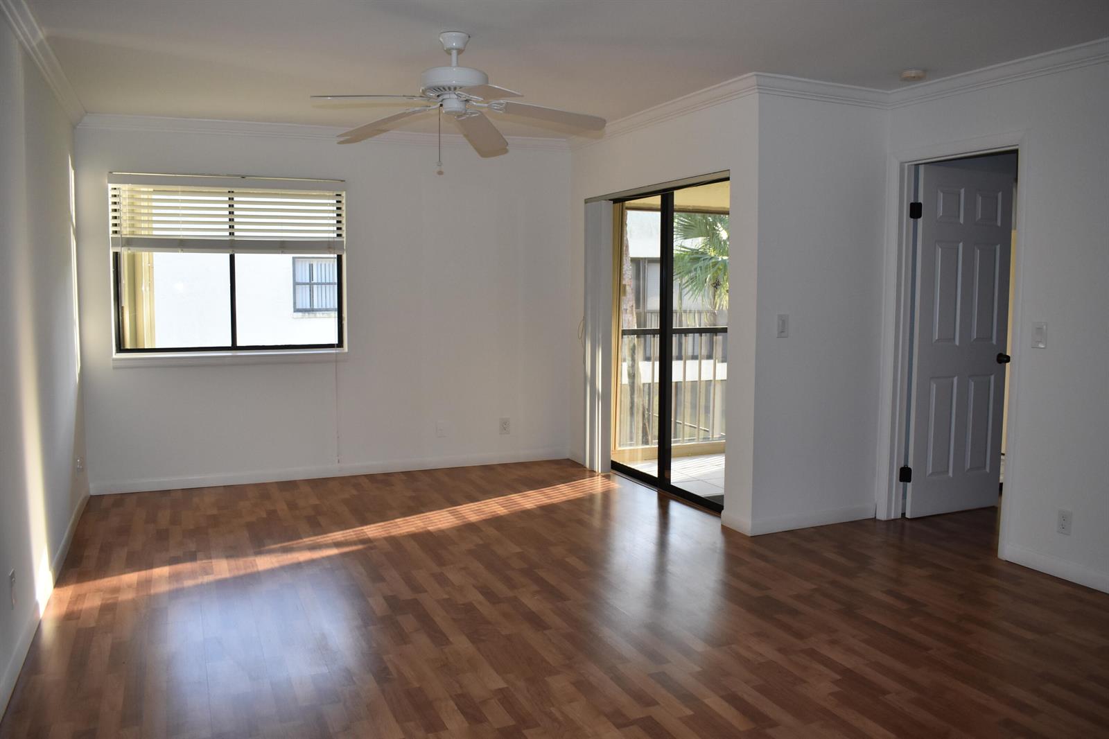 An empty room with wood-look flooring, a ceiling fan, a window, and a sliding glass door — 3374 Perimeter Drive, FL 33467, FL
