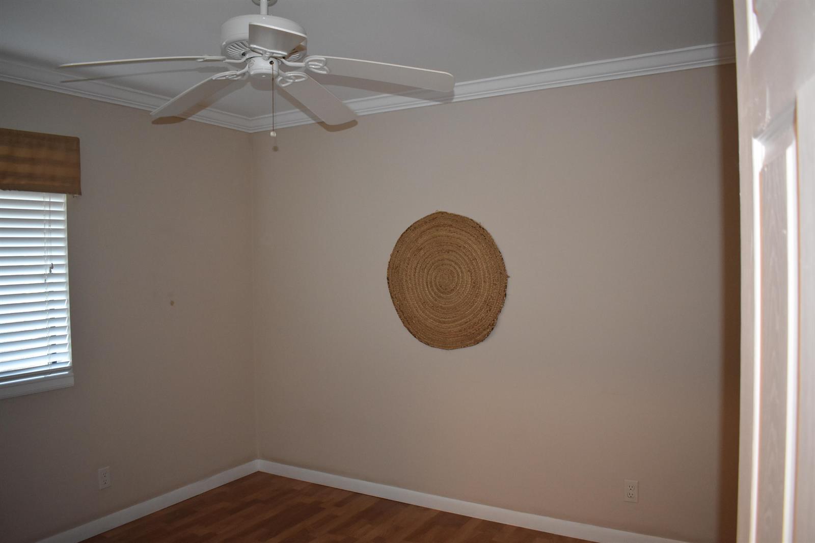 An empty room with beige walls, wood flooring, a ceiling fan, and a woven wall hanging — 3374 Perimeter Drive, FL 33467, FL
