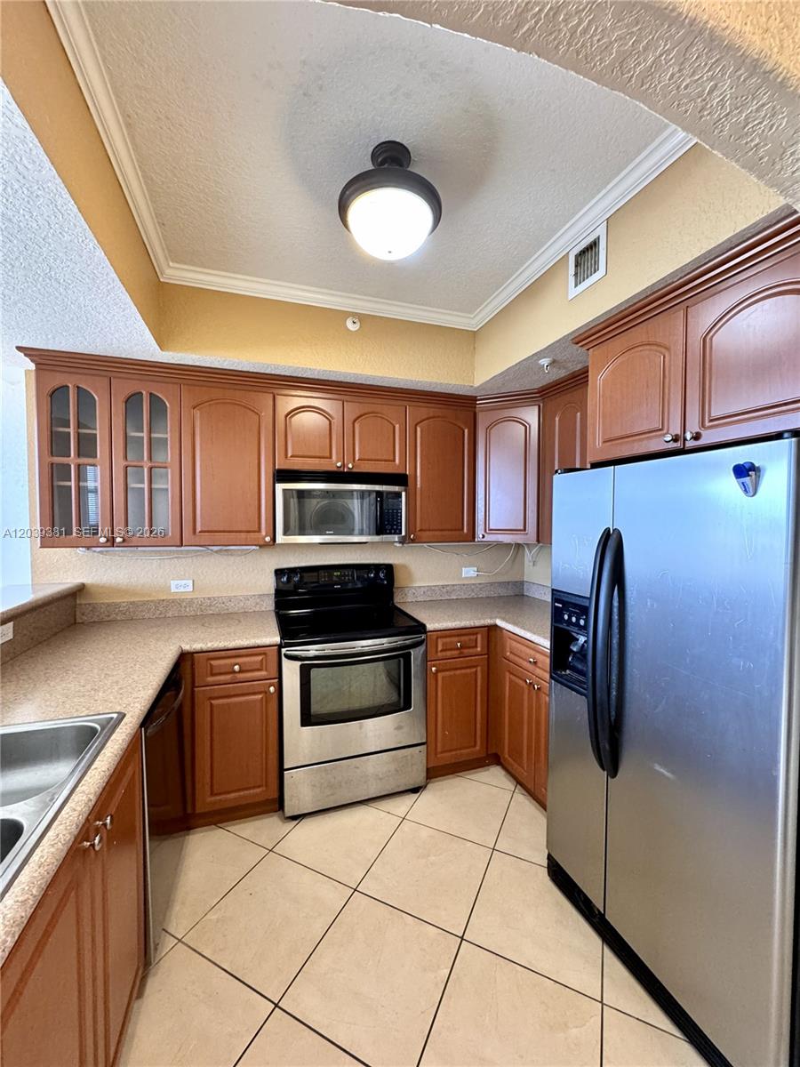 A kitchen features wood cabinets, stainless steel appliances, and beige tile flooring — 2301 SW 27th Ave # 1500, Miami FL 33145, MIAMI, FL