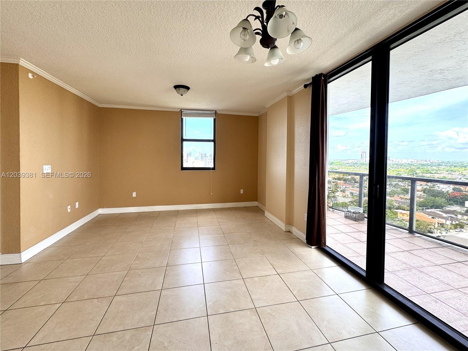 An empty room with tan walls, tile flooring, a chandelier, and a balcony with city views — 2301 SW 27th Ave # 1500, Miami FL 33145, MIAMI, FL