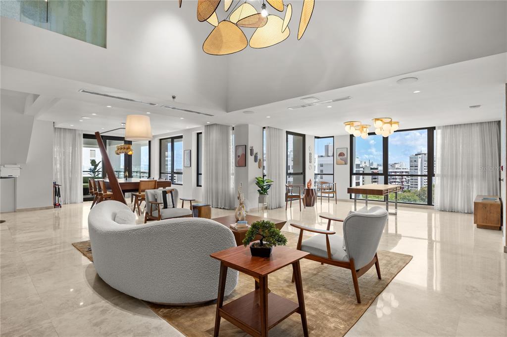A spacious, open-concept living and dining area features marble floors, high ceilings, and floor-to-ceiling windows — 1212 LUCHETTI ST UNIT PH, SAN JUAN, PR