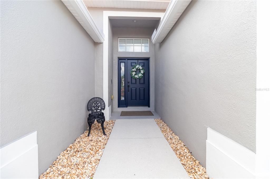 A concrete walkway leads to a dark blue front door with a decorative wreath — 8964 STONE HARBOUR LOOP, BRADENTON, FL