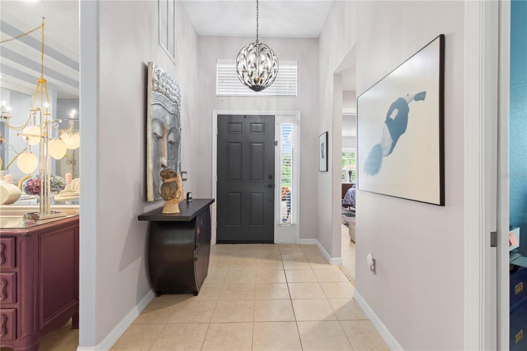 A foyer features tile flooring, a dark front door, a pendant light, and wall art — 8964 STONE HARBOUR LOOP, BRADENTON, FL