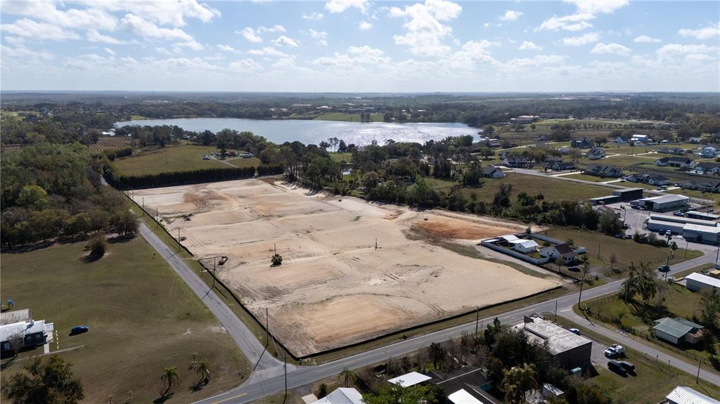 An aerial view shows a large, cleared rectangular plot of land near a lake — 12919 POMPANIC STREET, SAN ANTONIO, FL