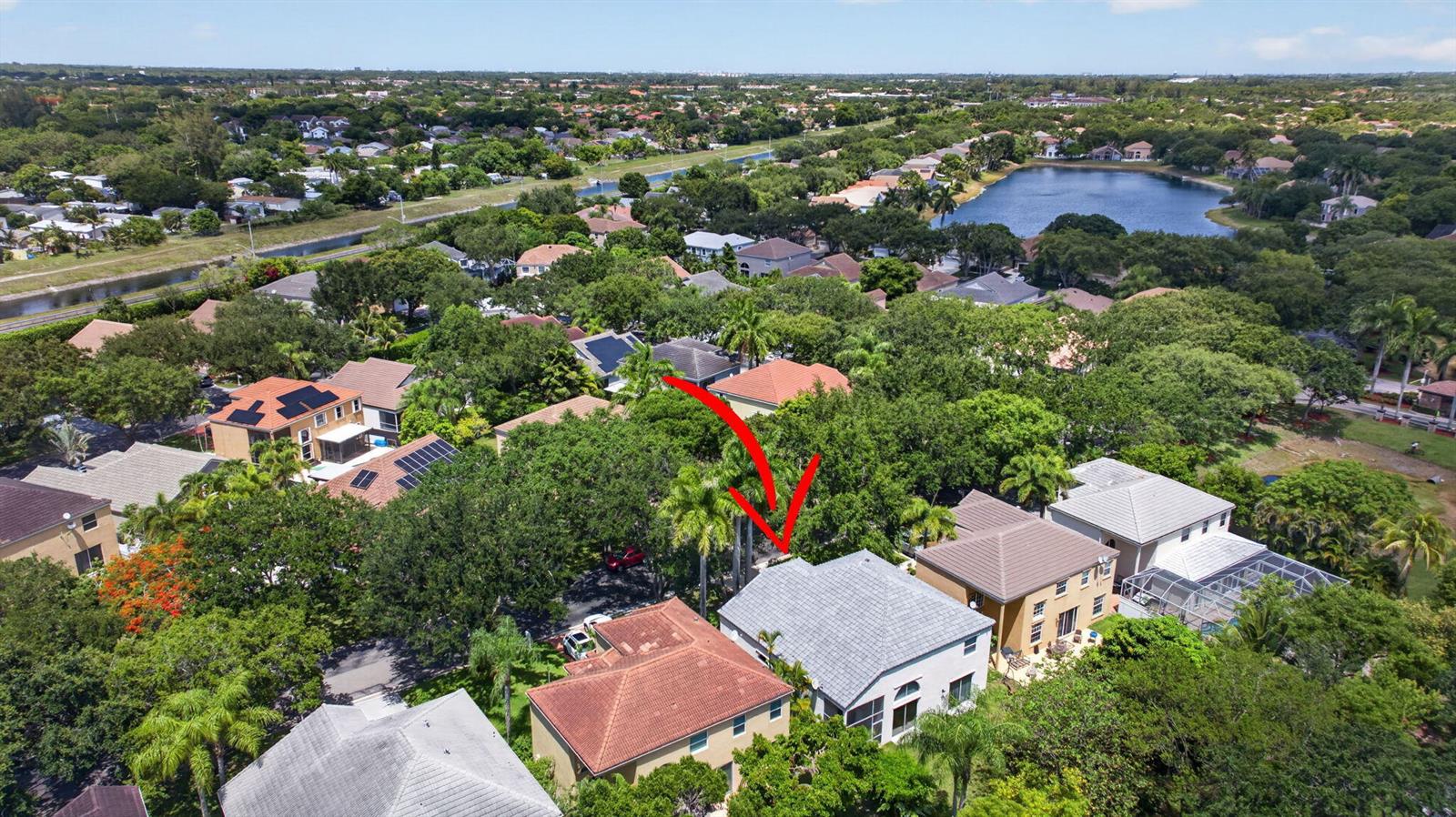 An aerial view of a residential neighborhood featuring houses with tiled roofs and lush trees — 6702 NW 80th Manor, Parkland FL 33067, PARKLAND, FL
