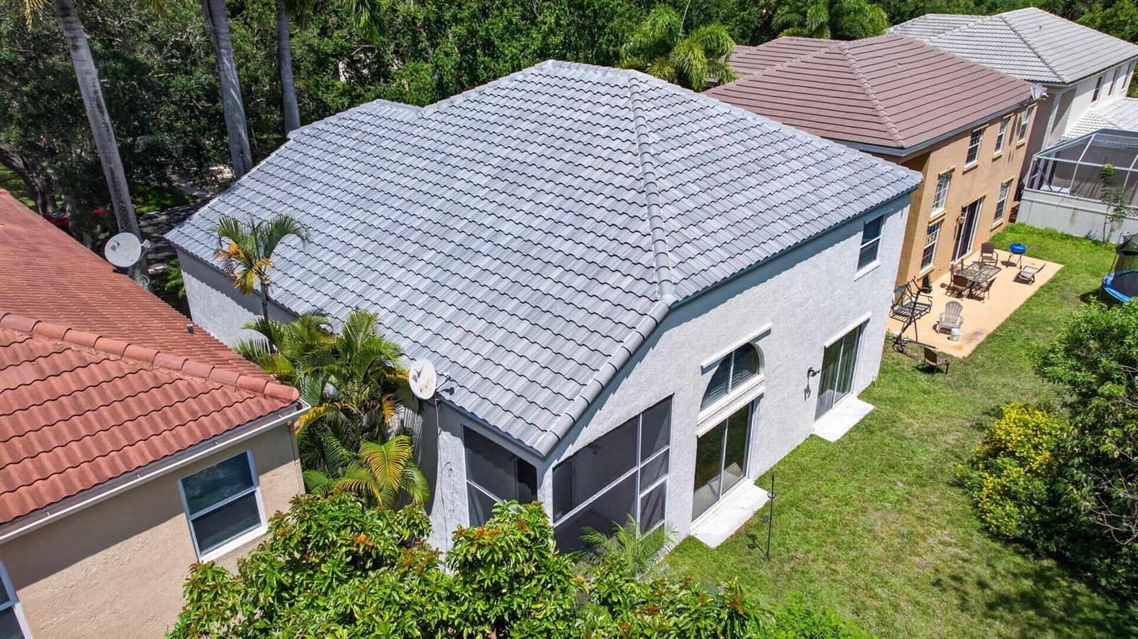 An aerial view of a two-story house with a gray tile roof and backyard patio — 6702 NW 80th Manor, Parkland FL 33067, PARKLAND, FL