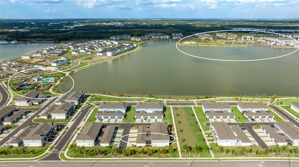 An aerial view shows a residential community with townhomes surrounding a large central lake — 1808 FENDER LANE, SARASOTA, FL