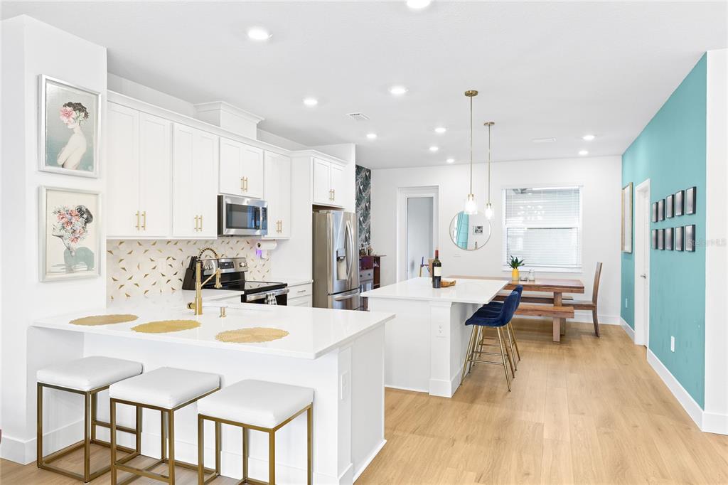 A modern kitchen features white cabinetry, a central island with bar seating, and light flooring — 1808 FENDER LANE, SARASOTA, FL