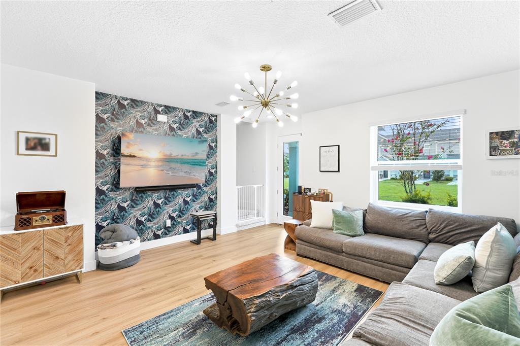 A living room features a patterned accent wall, a large sectional sofa, and a chandelier — 1808 FENDER LANE, SARASOTA, FL