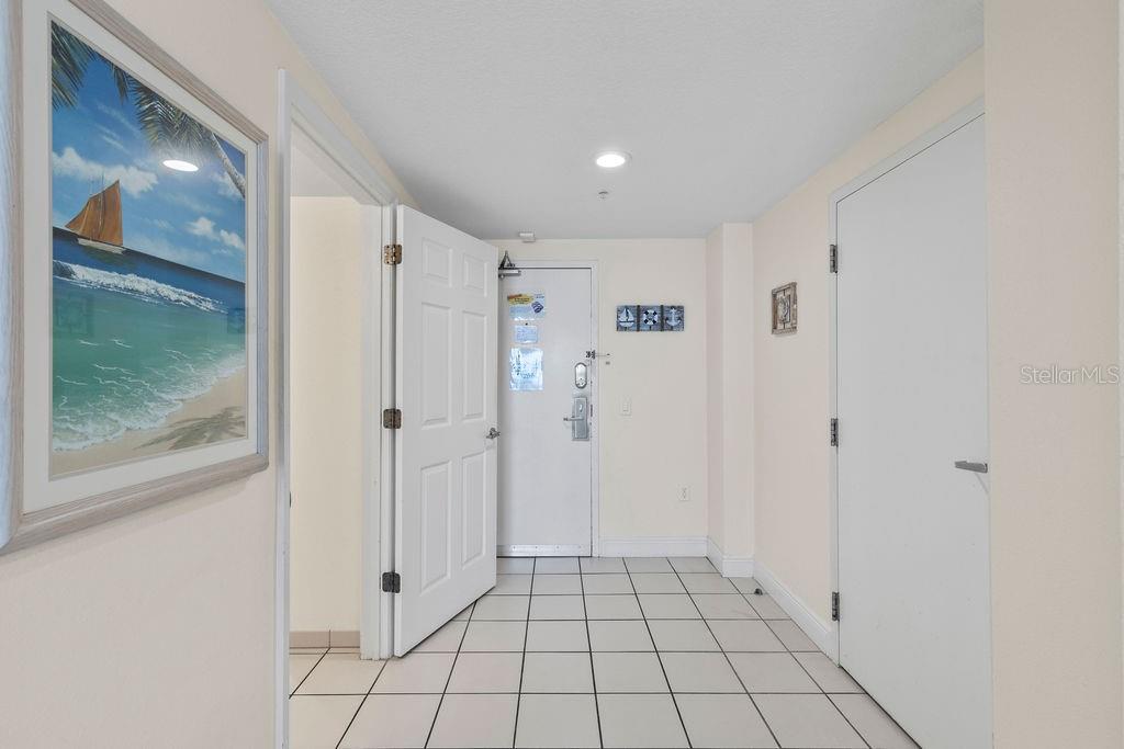 An entryway features white tiled floors, a white front door, and a framed beach painting — 2700 N ATLANTIC AVENUE UNIT 342, DAYTONA BEACH, FL