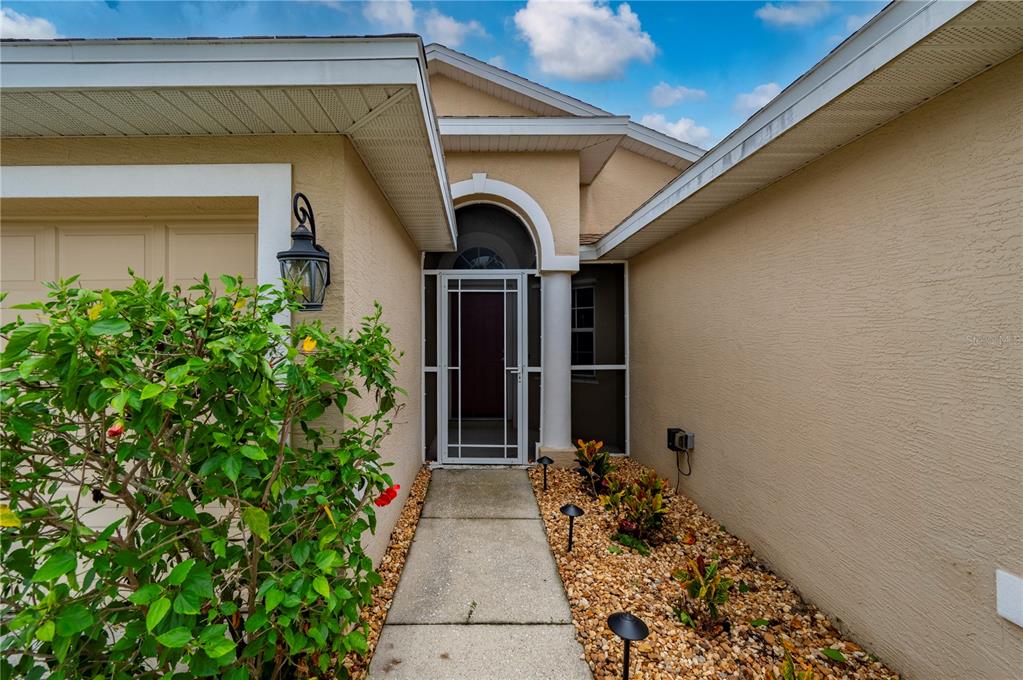 A concrete walkway leads to the front entrance of a house with a screen door — 1611 SCARLETT AVENUE, NORTH PORT, FL