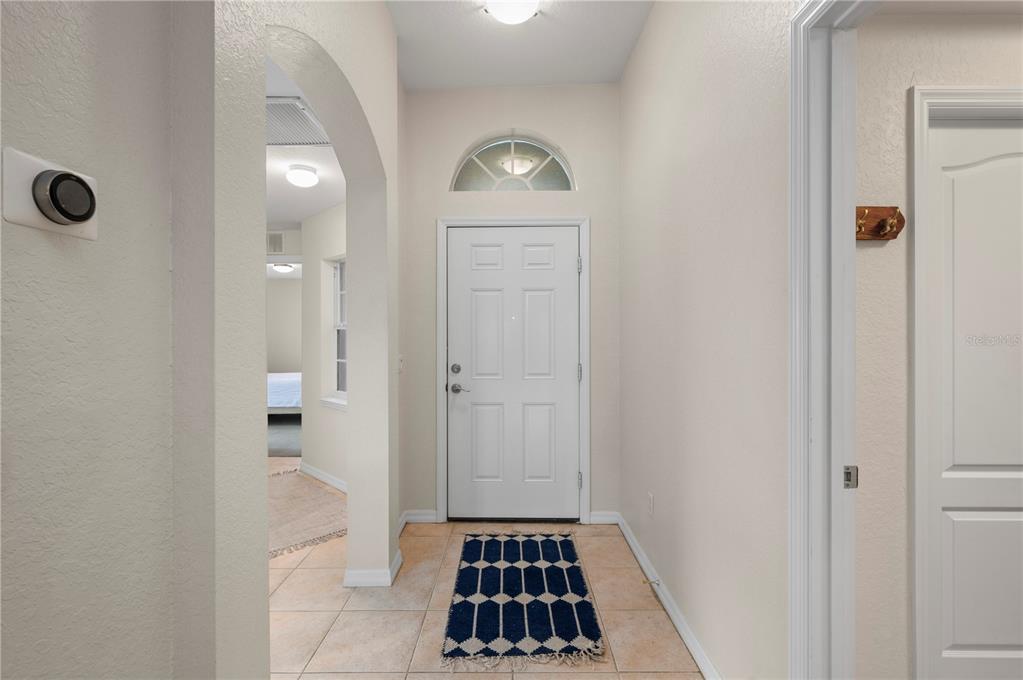 An entryway features a white front door with a transom window and tiled flooring — 1611 SCARLETT AVENUE, NORTH PORT, FL