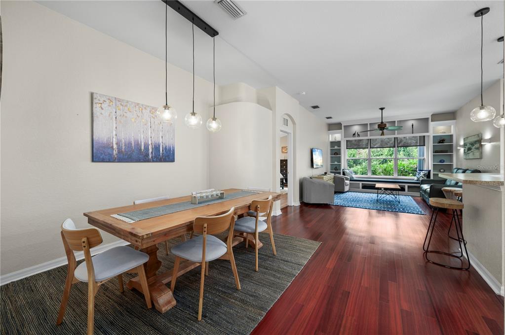 A dining area with a wooden table and pendant lights opens into a living room — 1611 SCARLETT AVENUE, NORTH PORT, FL
