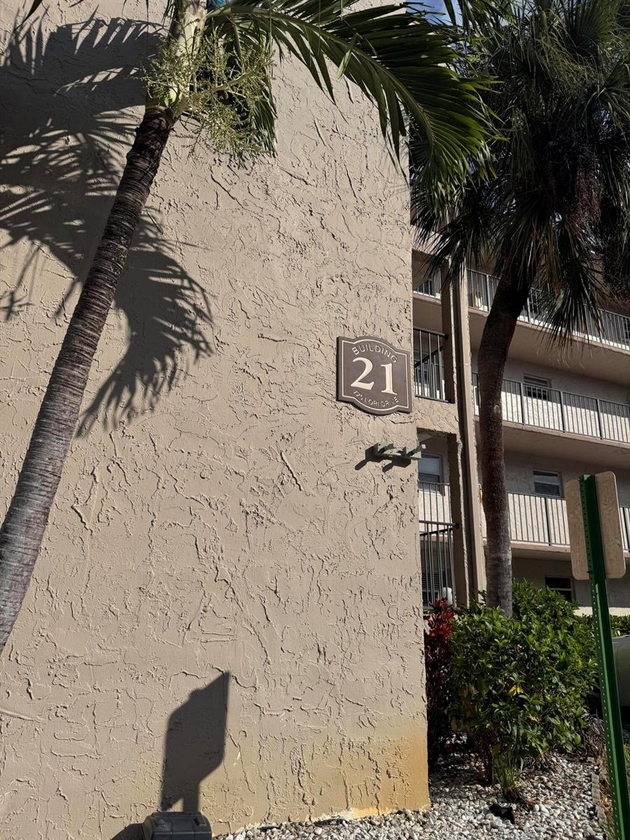 A tan stucco building exterior features a sign labeled Building 21 and palm trees — 725 Lori Drive # 107, Palm Springs FL 33461, PALM SPRINGS, FL