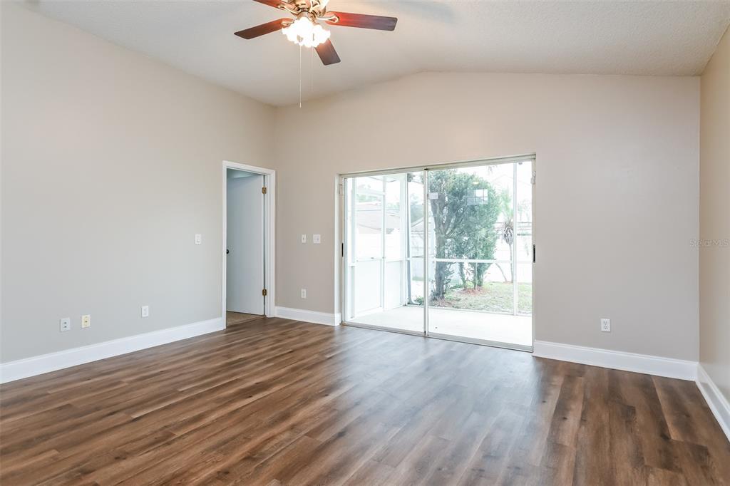 An empty room with wood-look flooring, a ceiling fan, and sliding glass doors to a patio — 4912 SAUSALITO LANE, KISSIMMEE, FL