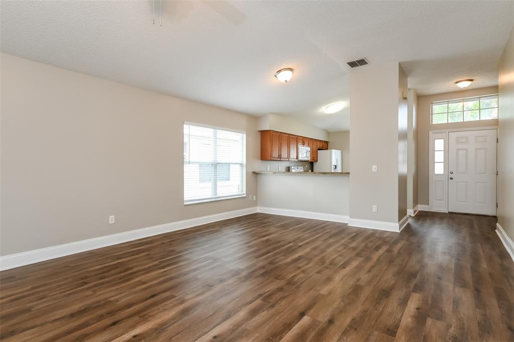 A living room with wood-look flooring, a breakfast bar, and an adjacent kitchen area — 4912 SAUSALITO LANE, KISSIMMEE, FL