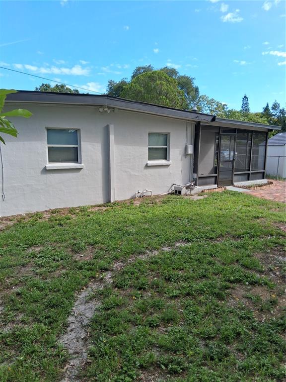 The exterior of a light-colored house features two windows and a screened-in porch — 1603 SCOTT STREET, CLEARWATER, FL