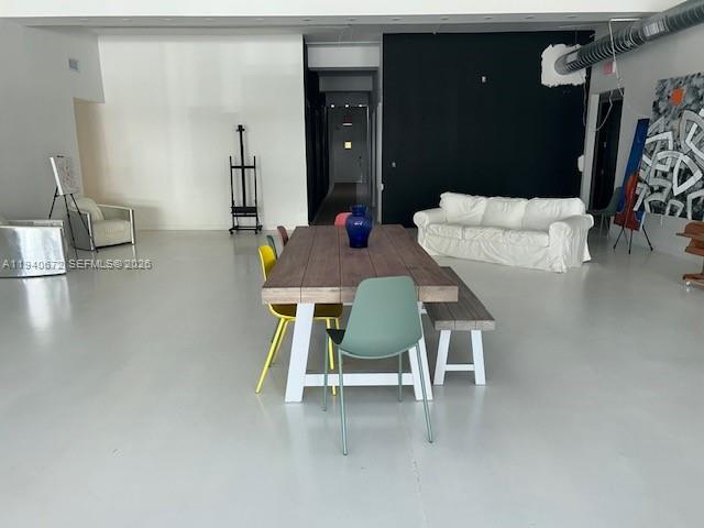 A modern, open-concept room features a wooden dining table, a white sofa, and polished floors — 5600 NW 7 Ave, Miami FL 33127, MIAMI, FL