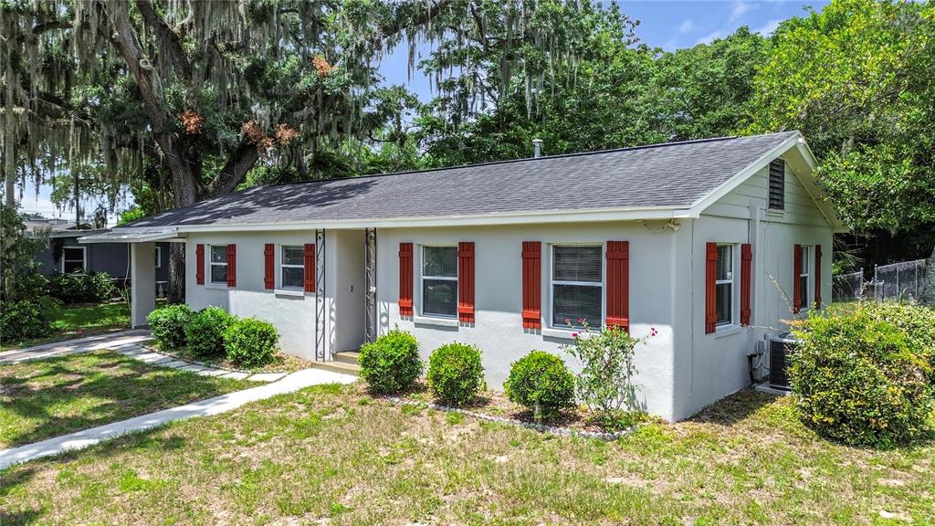 A single-story house with light-colored stucco walls, a dark roof, and red window shutters — 125 TROUT AVENUE, INVERNESS, FL