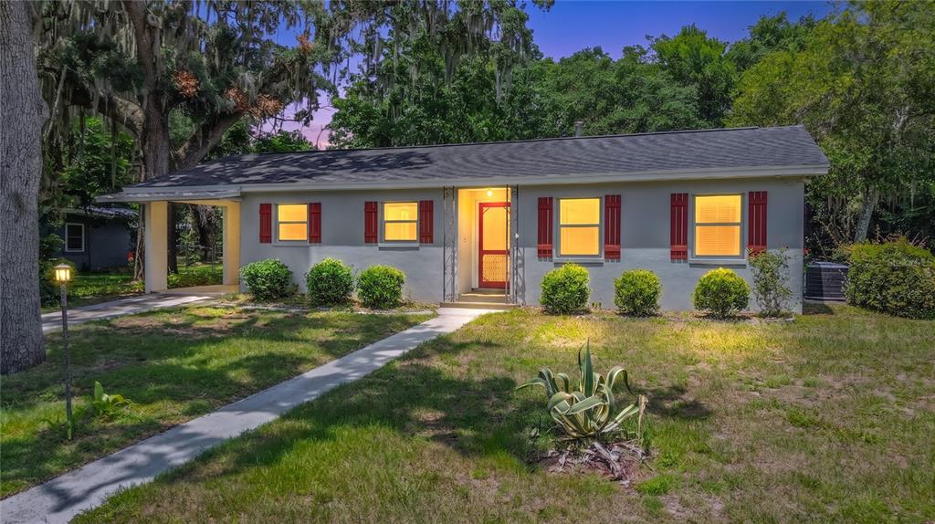 A single-story gray house with a carport, red shutters, and a front walkway — 125 TROUT AVENUE, INVERNESS, FL