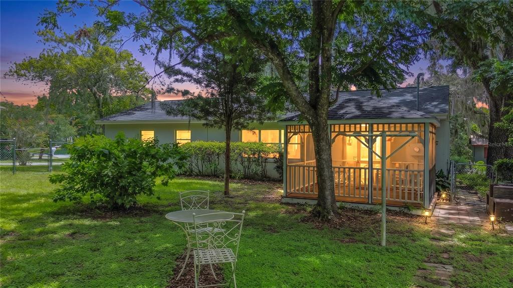 A backyard view of a house with a screened-in porch and a small patio set — 125 TROUT AVENUE, INVERNESS, FL