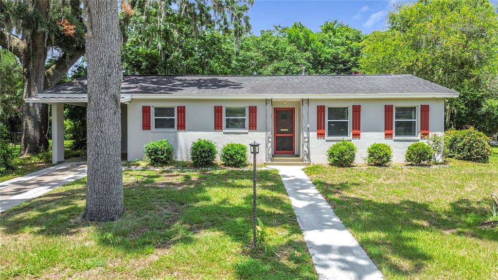 A single-story house with a gray roof, white siding, red shutters, and a carport — 125 TROUT AVENUE, INVERNESS, FL