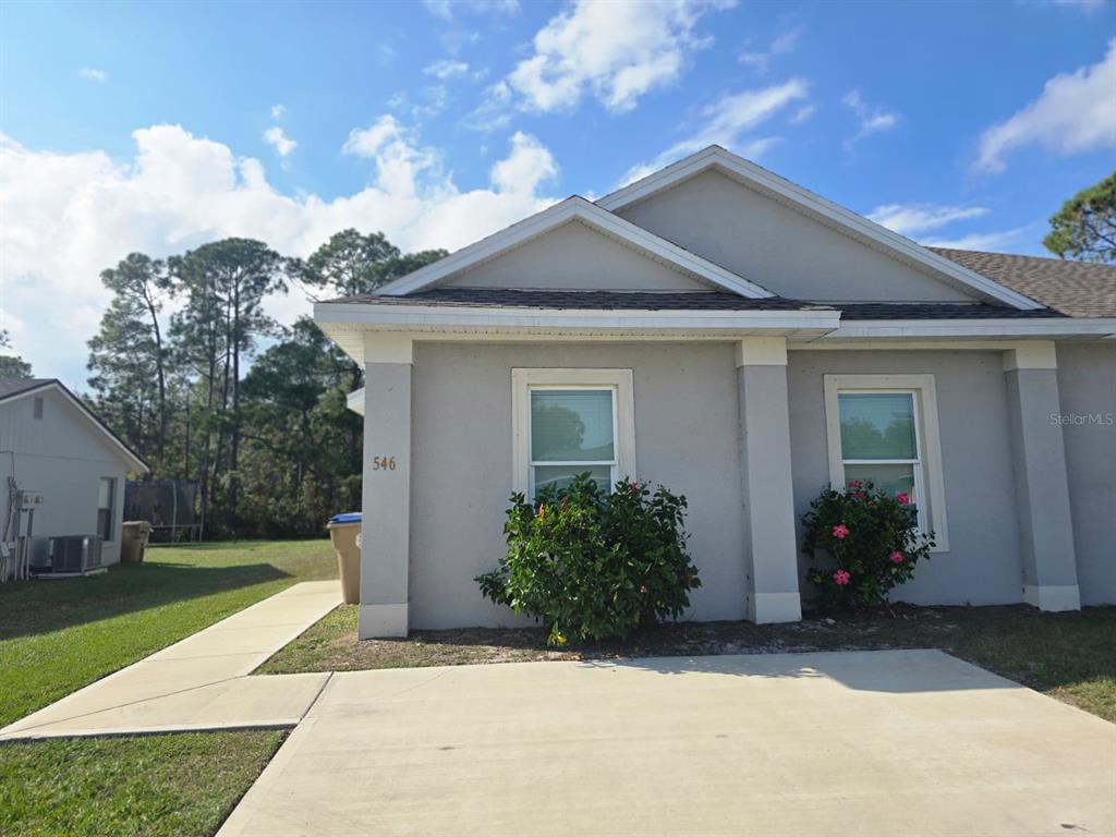 A single-story house with a concrete driveway, two windows, and two bushes in front — 546 IMPERIAL PL, KISSIMMEE, FL