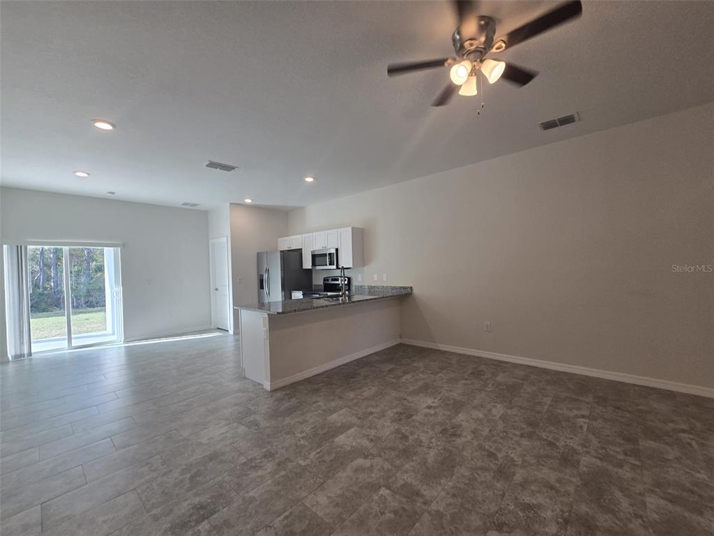 An open-concept kitchen and living area features gray tile flooring and a granite-topped island — 546 IMPERIAL PL, KISSIMMEE, FL