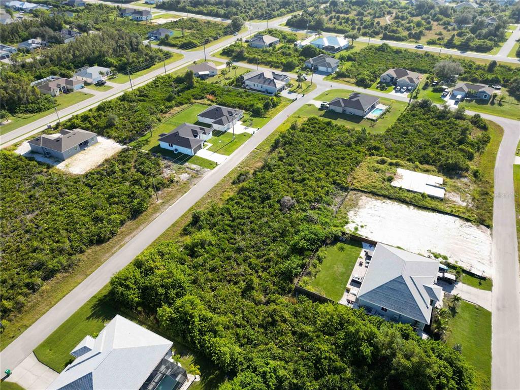 An aerial view shows several single-family homes surrounded by undeveloped, wooded lots — 13541 ABUTILON LANE, PORT CHARLOTTE, FL