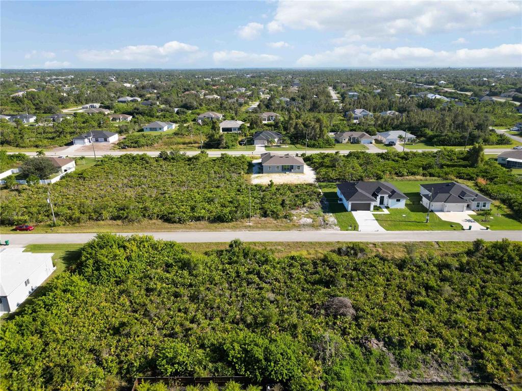 An aerial view shows a residential neighborhood with several houses surrounded by dense vegetation — 13541 ABUTILON LANE, PORT CHARLOTTE, FL