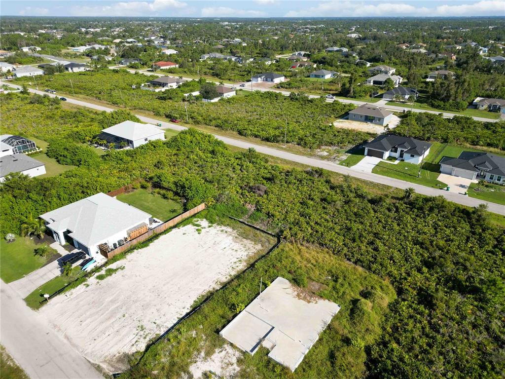An aerial view shows a cleared residential lot with a concrete foundation slab — 13541 ABUTILON LANE, PORT CHARLOTTE, FL