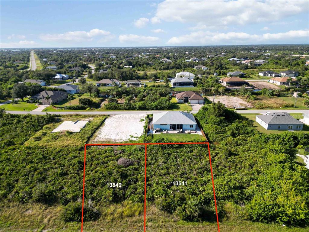 An aerial view shows two vacant, brush-covered residential lots adjacent to a house — 13541 ABUTILON LANE, PORT CHARLOTTE, FL