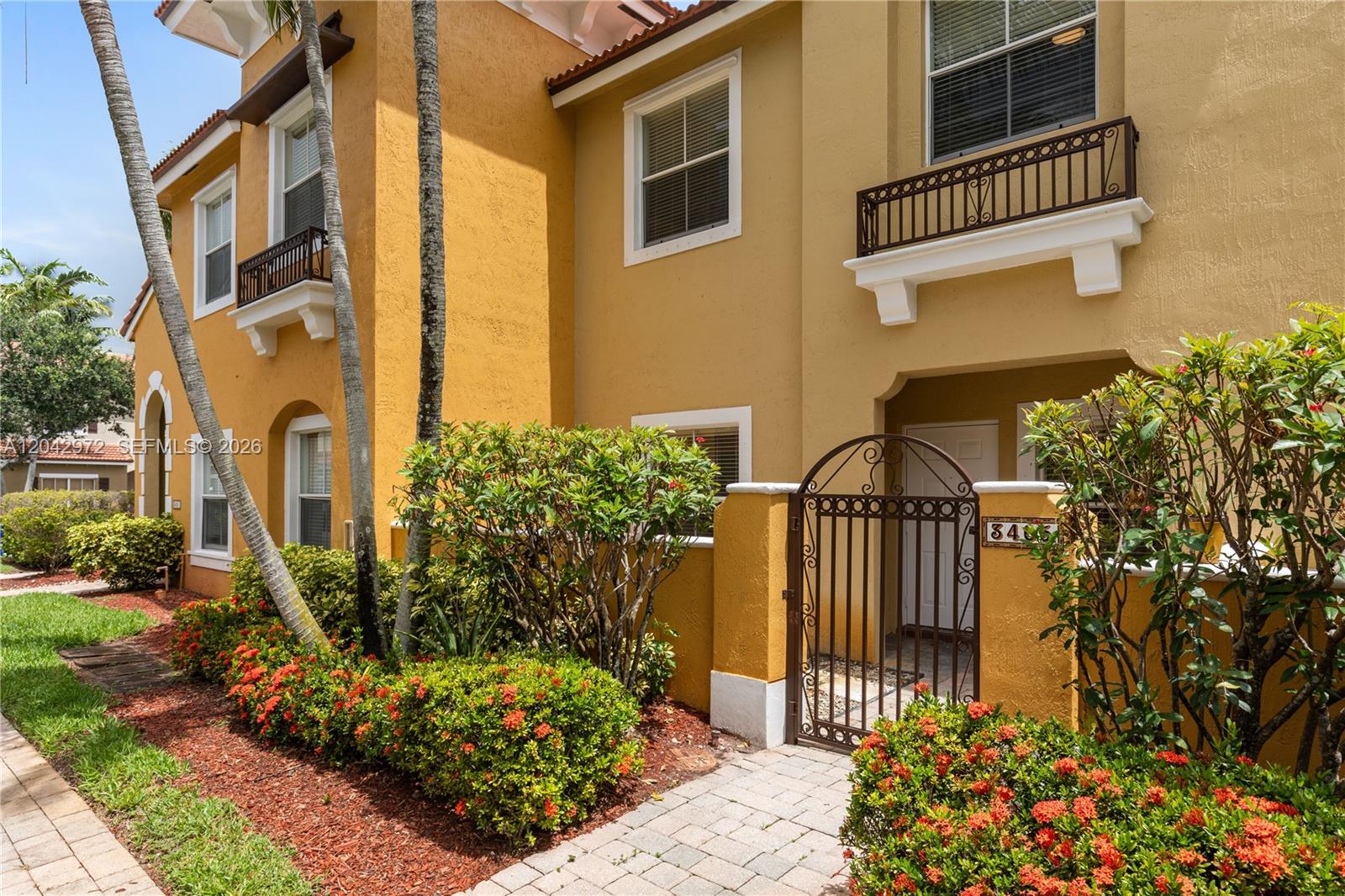 A two-story yellow stucco townhouse features a gated courtyard entrance and lush landscaping — 3405 Merrick Ct # 1209, Margate FL 33063, MARGATE, FL