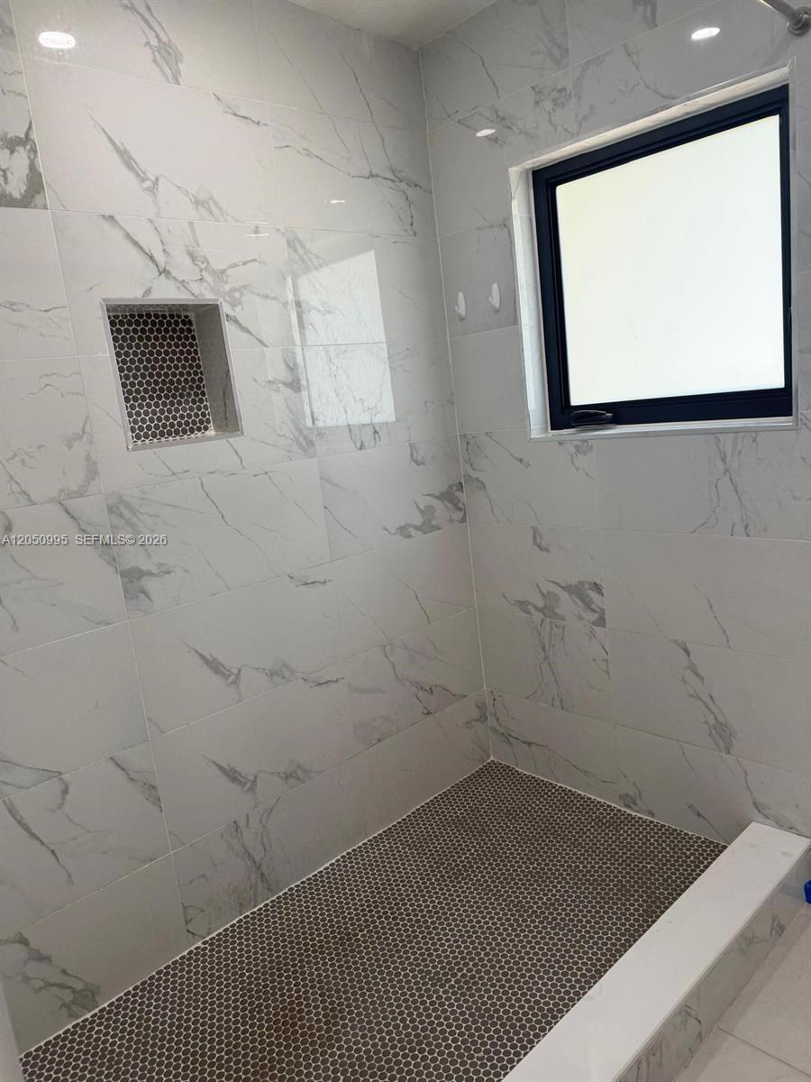 A walk-in shower features white marble-look wall tiles, a dark penny-tile floor, and a niche — 765 W 70th Pl # 1, Hialeah FL 33014, HIALEAH, FL
