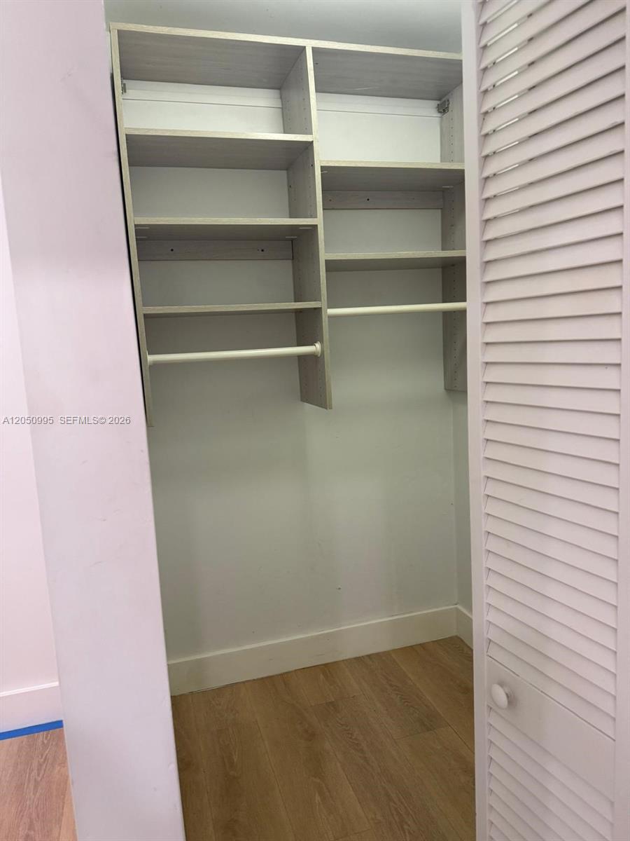 A closet features light wood-toned shelving and hanging rods against white walls — 765 W 70th Pl # 1, Hialeah FL 33014, HIALEAH, FL