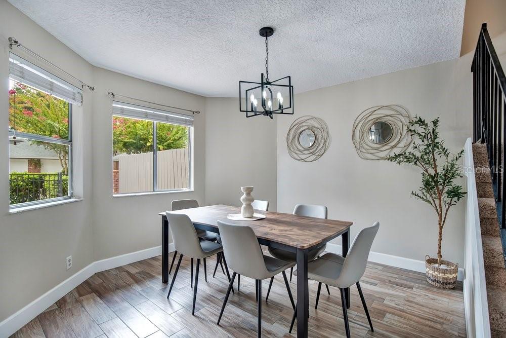 A dining room features a wood-top table, six gray chairs, a chandelier, and two windows — 604 CHESTNUT OAK CIRCLE UNIT 106, ALTAMONTE SPRINGS, FL