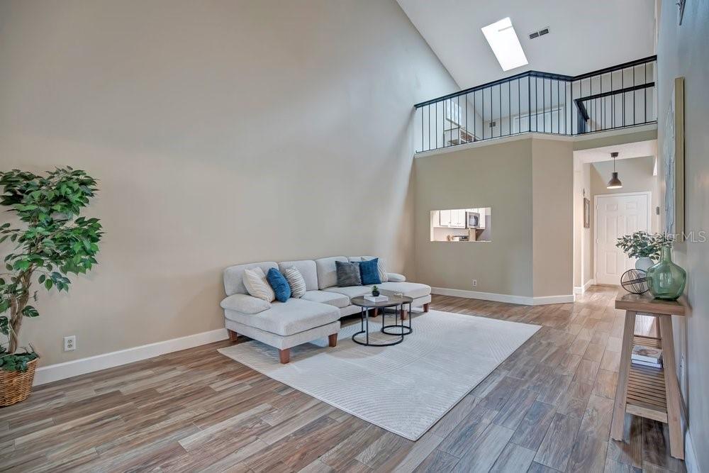A living room with high ceilings, a lofted balcony, and light wood-look flooring — 604 CHESTNUT OAK CIRCLE UNIT 106, ALTAMONTE SPRINGS, FL