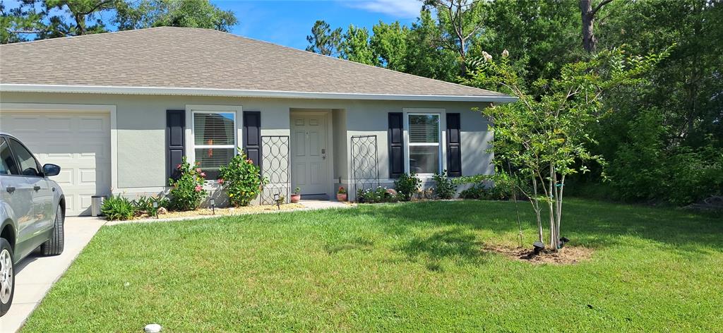 A single-story house with a light-colored exterior, dark shutters, and a front-facing garage — 16 PRINCETON LANE, PALM COAST, FL