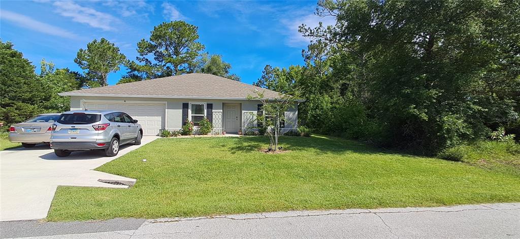 A single-story house with a two-car garage and a driveway sits on a grassy lot — 16 PRINCETON LANE, PALM COAST, FL