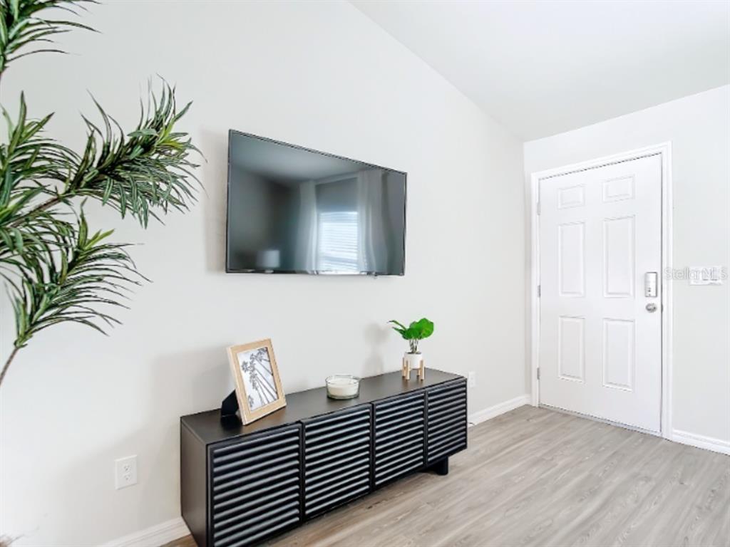 A living room features a wall-mounted television above a black slatted media console — 100 PORT ROYAL DRIVE, PALM COAST, FL