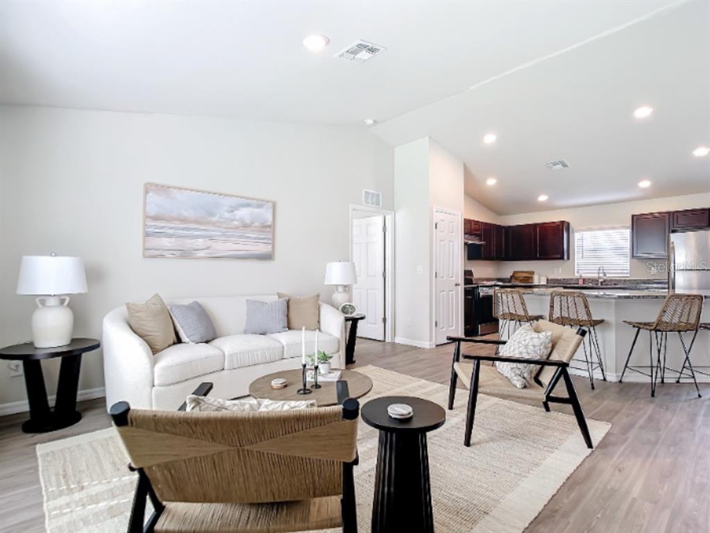 A living room with a white sofa, two woven chairs, and an open-concept kitchen — 100 PORT ROYAL DRIVE, PALM COAST, FL