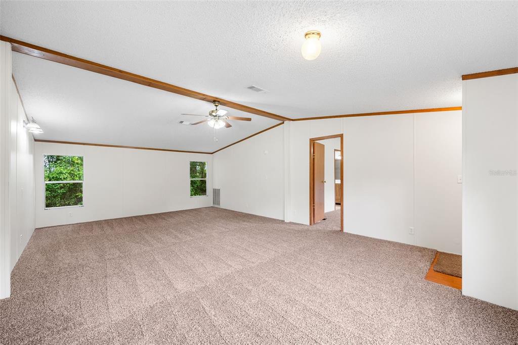 An empty room with beige carpet, white walls, a vaulted ceiling, and a ceiling fan — 4296 SE COUNTY ROAD 18, LAKE CITY, FL