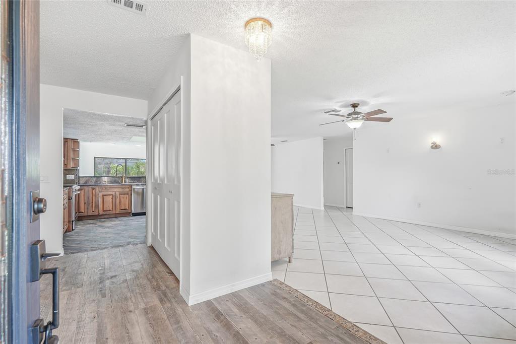 An entryway with wood-look flooring leads to a kitchen and a tiled living area — 4509 MITCHER ROAD, NEW PORT RICHEY, FL