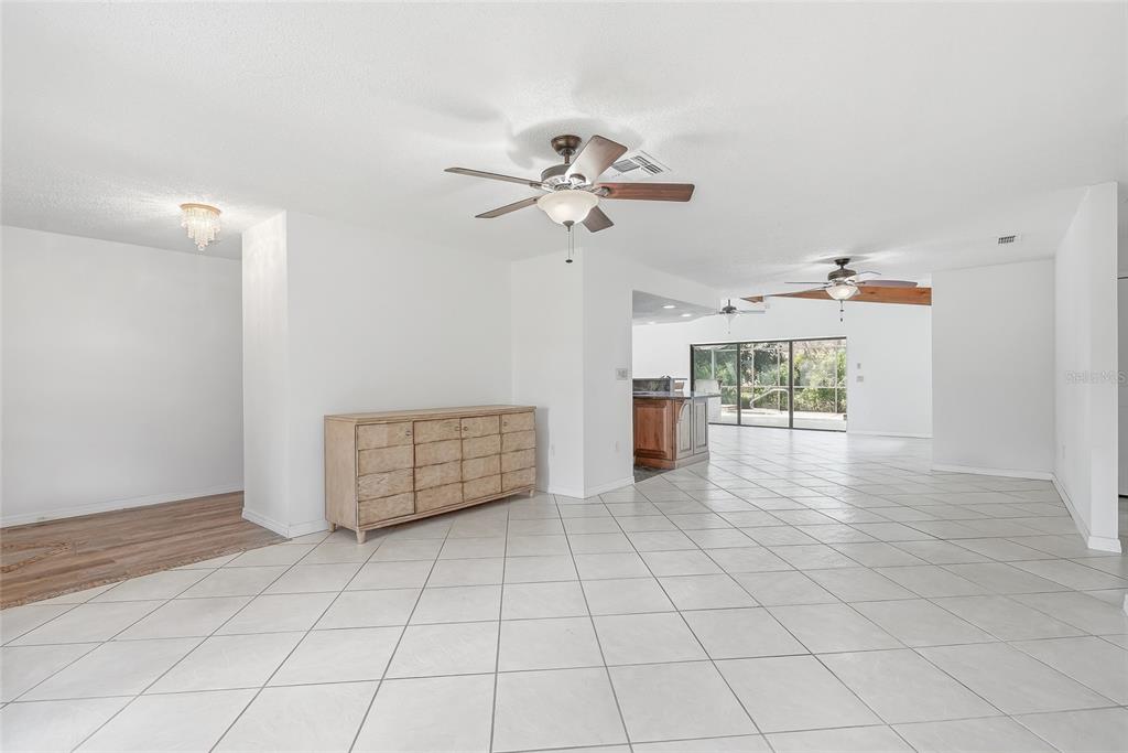 A spacious room with white tiled floors, a wooden dresser, and two ceiling fans — 4509 MITCHER ROAD, NEW PORT RICHEY, FL
