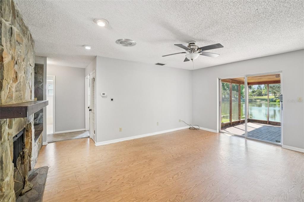 A living room with light wood flooring, a stone fireplace, and sliding doors to a patio — 2024 W SITKA STREET, TAMPA, FL