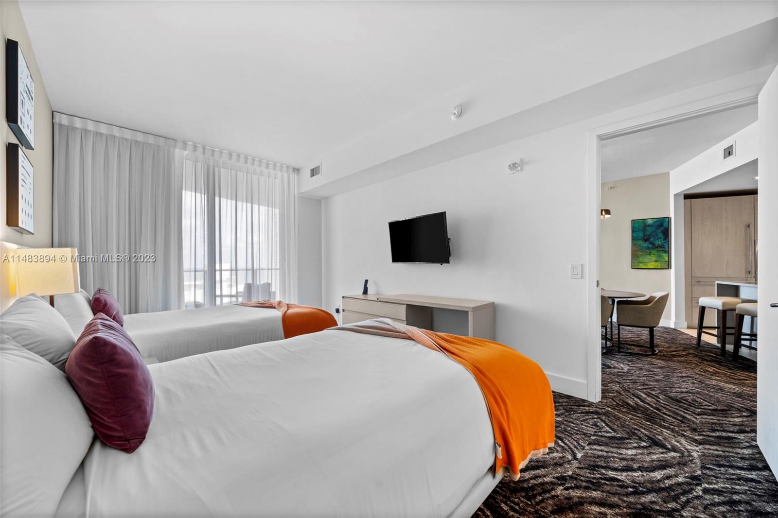 A bedroom with two beds, a wall-mounted television, and an adjacent dining area — 4111 S Ocean Dr # 1406, Hollywood FL 33019, HOLLYWOOD, FL