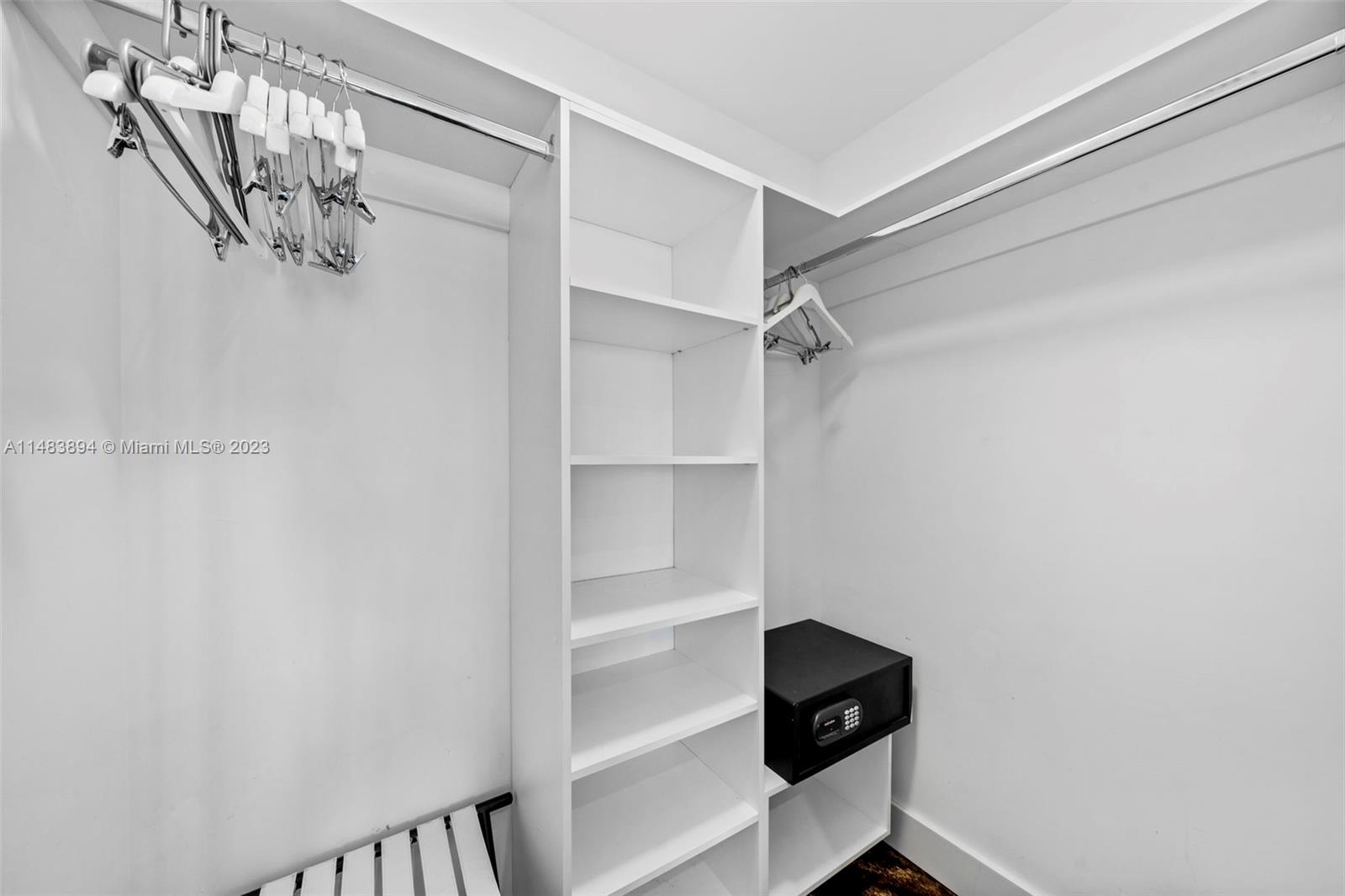 A white walk-in closet features hanging rods, open shelving, and a black wall safe — 4111 S Ocean Dr # 1406, Hollywood FL 33019, HOLLYWOOD, FL
